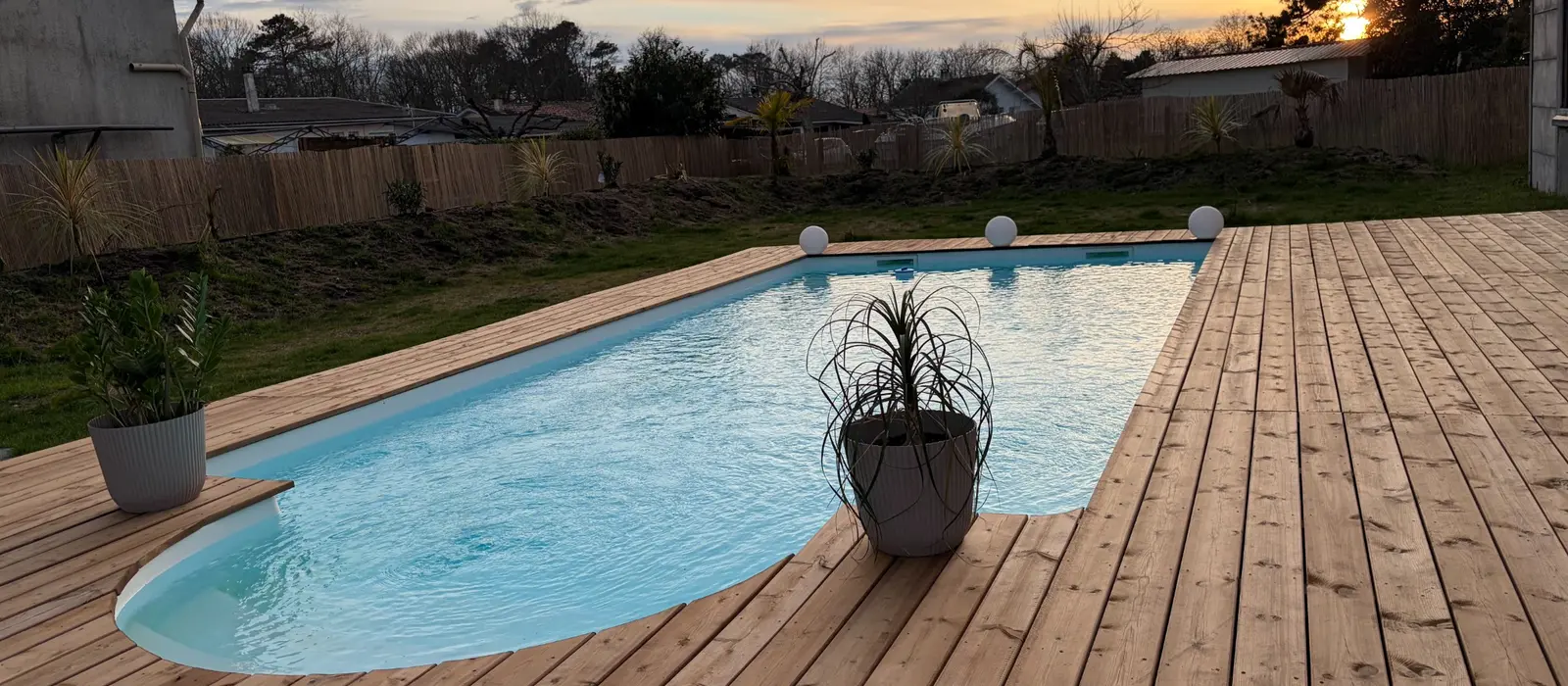 Terrasse en bois autour d’une piscine dans un jardin arboré