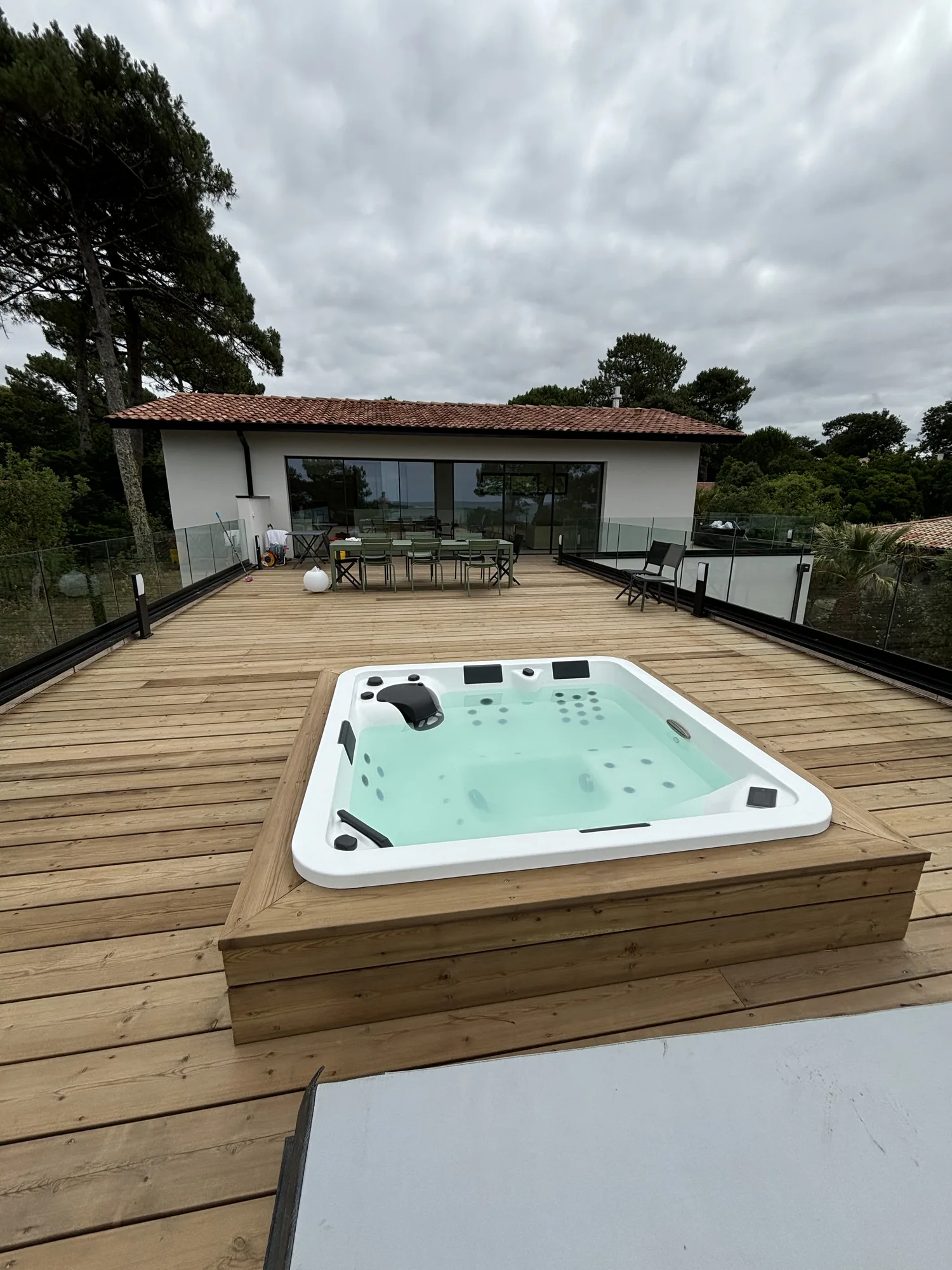 Terrasse en pin du Nord de 70 m² avec spa entouré d’un habillage en bois surélevé à Biganos à Biganos