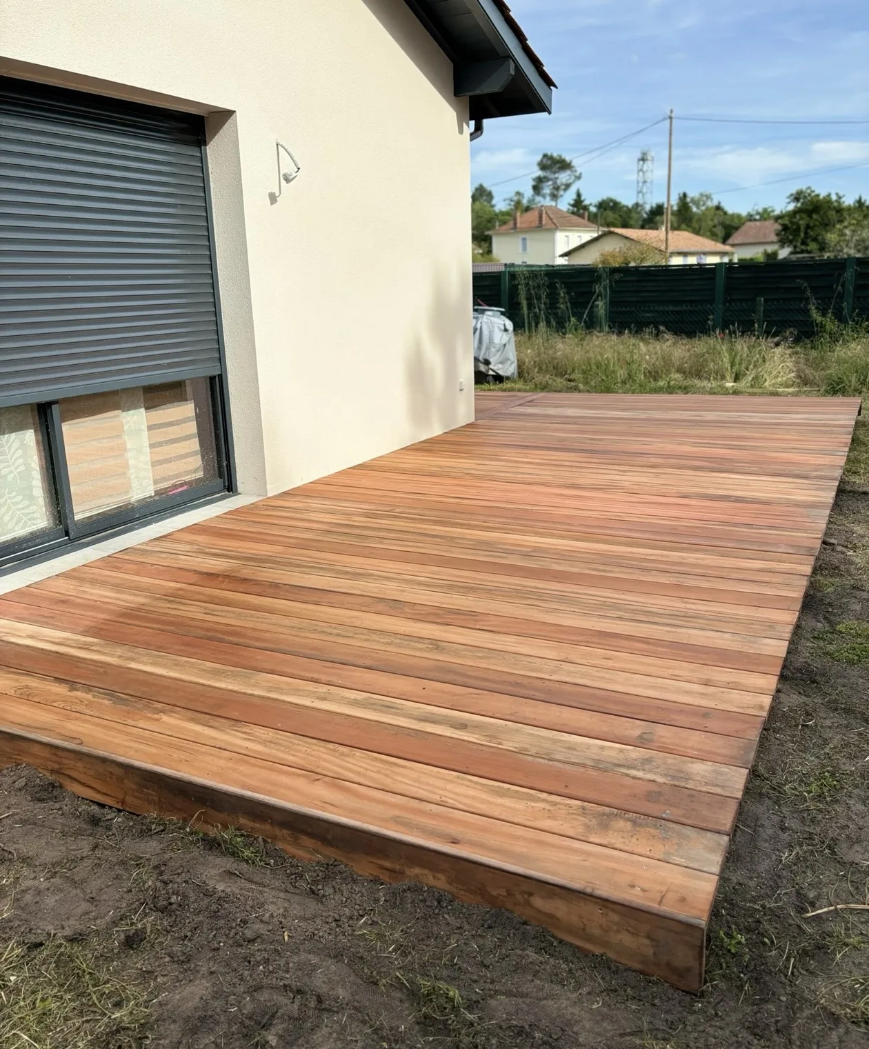 Grande terrasse en bois posée le long d’une maison